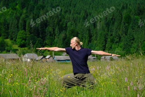 Preview: Young man practicing yoga exercises in green nature