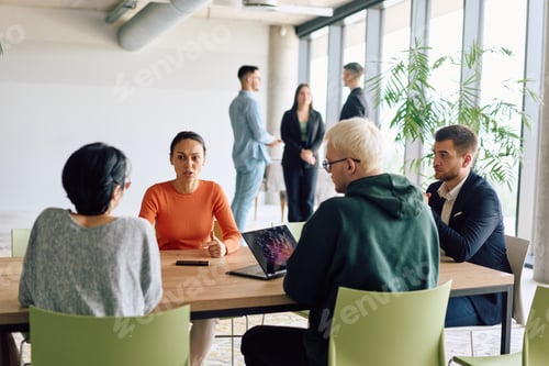 Preview: A diverse team of business professionals engaged in a discussion around a conference table in an