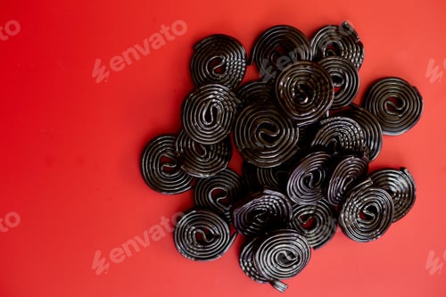 Preview: Flat lay tasty black liquorice candies on red background
