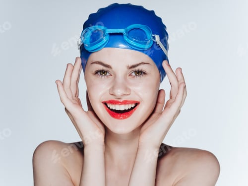 Preview: Emotional woman wearing a blue swimming cap grimaces on a light background cropped view