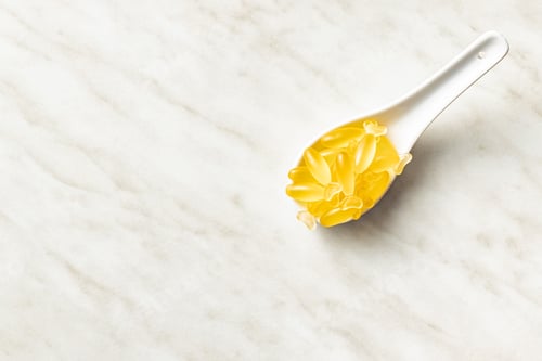 Preview: Fish oil capsules. Yellow omega 3 pills in spoon on white table.