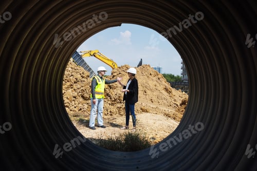 Preview: View through a large drainage pipe in a construction site.