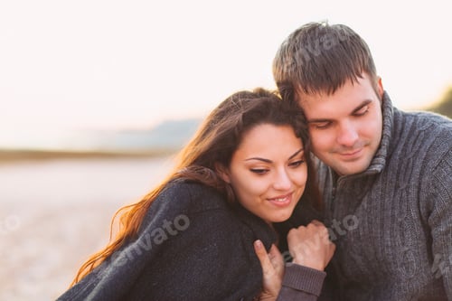 Preview: Portrait of young happy couple laughing in a cold day by the autumn sea
