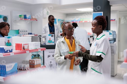 Preview: African american pharmacist helping woman buying supplements in drugstore