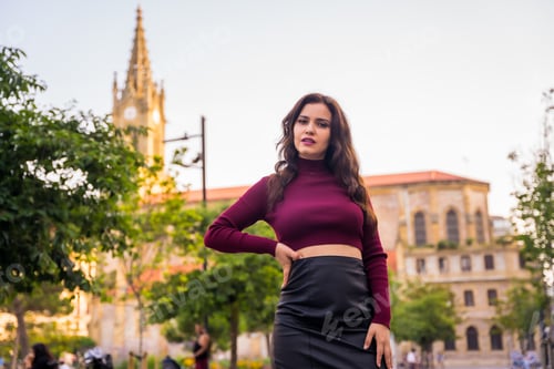 Preview: Portrait of a brunette model with a leather skirt next to a church visiting the city, lifestyle