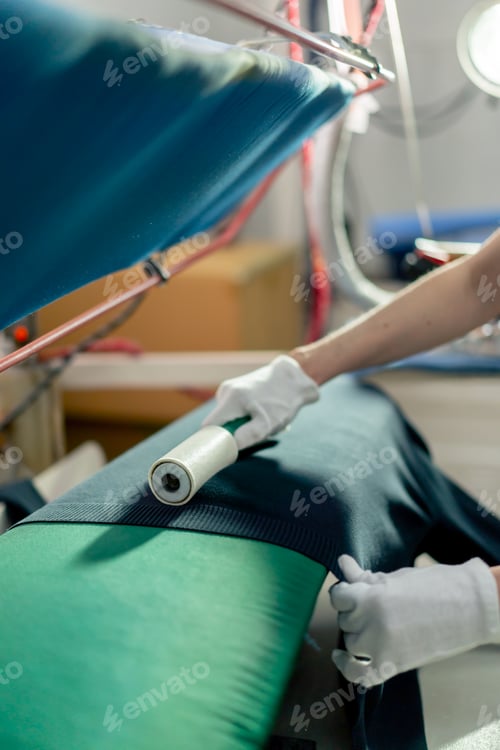 Preview: close up professional dry cleaner young girl uses an adhesive roller to remove wool on a black