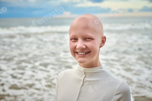 Preview: Close up portrait of smiling hairless girl with alopecia in white futuristic costume on sea