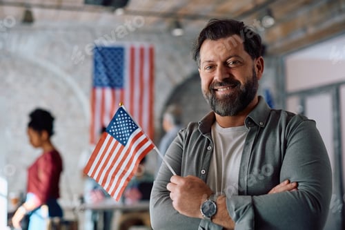 Preview: Happy American man with national flag on election day looking at camera.