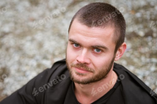 Preview: Portrait of young man outdoors with an unshaven face in a dark sweater