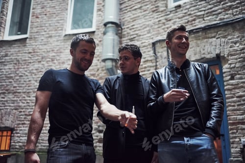 Preview: Smoking together. Three male friends stands outside the bar. Having conversation. In nice clothes