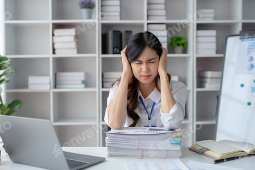 Preview: Young Asian businesswoman stressed by overwork at office.