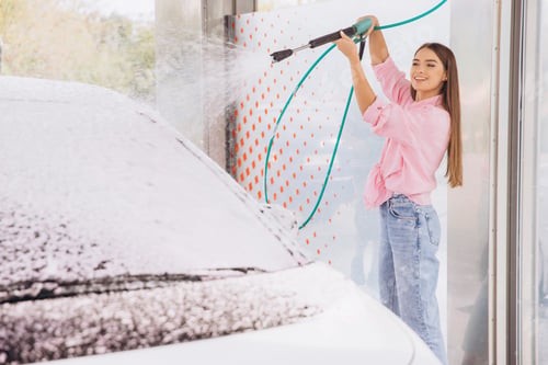 Preview: Young Woman Enjoys Cleaning Car with High-Pressure Hose at Wash