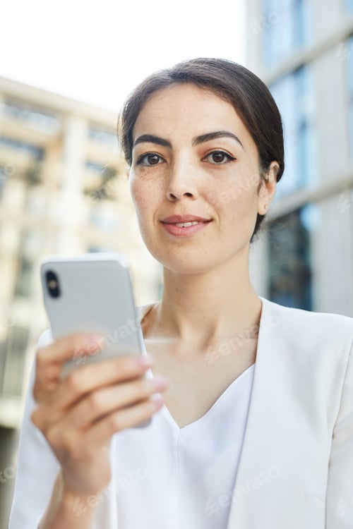 Professional Woman Holding Smartphone in Urban Setting