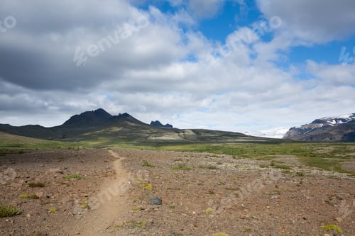 Preview: Scenic mountain landscape with dirt path under partly cloudy sky