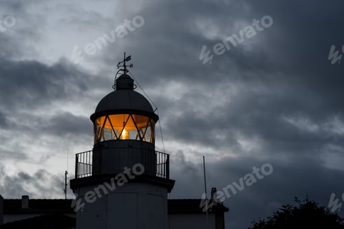 Preview: Shining lighthouse against cloudy sky