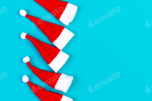Preview: Top view od stylish red Santa hats on colorful background. Merry Christmas concept with copy space