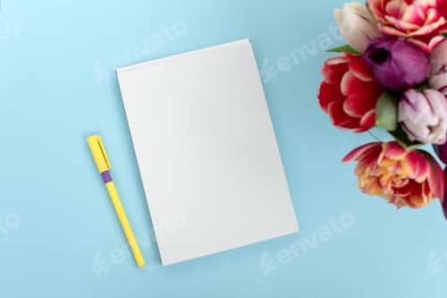 Preview: Top view of a blue table with a mockup of blank notebooks with a bouquet of tulips on the side.