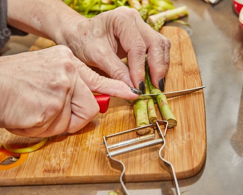 Preview: Chef prepares Asparagus in the kitchen on wooden board according to recipe from the Internet