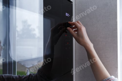 Preview: Woman heats food in the microwave. Kitchen appliances built into furniture.