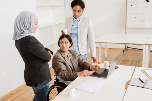 Preview: Three multiracial women discussing project while working at office