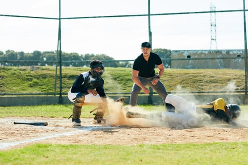 Preview: Full length shot of a young baseball player reaching base during a match on the field