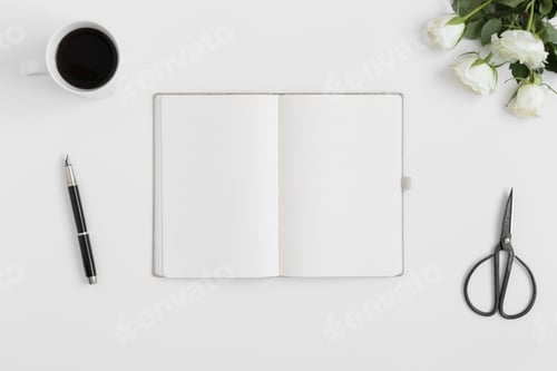Preview: Top view of a notebook mockup with a bouquet of roses and workspace accessories on a white table.