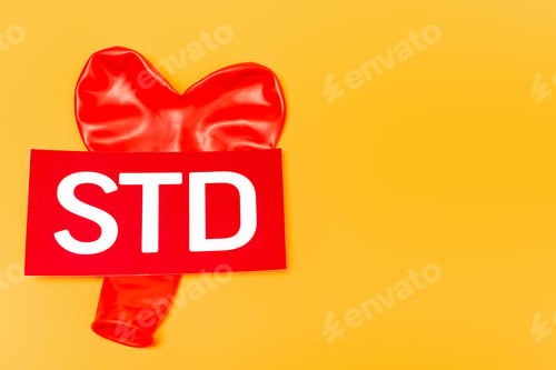 Preview: top view of heart-shaped balloon near std lettering isolated on orange
