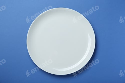 Preview: Empty white ceramic plate on blue background, top view