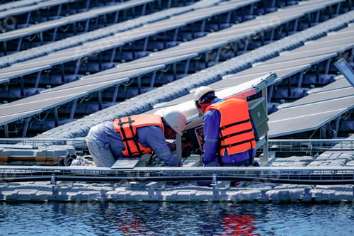 Preview: Local worker working at floating solar panels platform on the water of solar cell power plant.