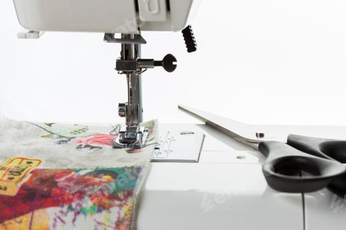 Preview: Seamstress working on colorful fabric with scissors and sewing machine in a bright workspace