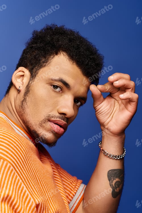 Preview: Handsome man striking a pose against a vibrant blue background with stylish confidence