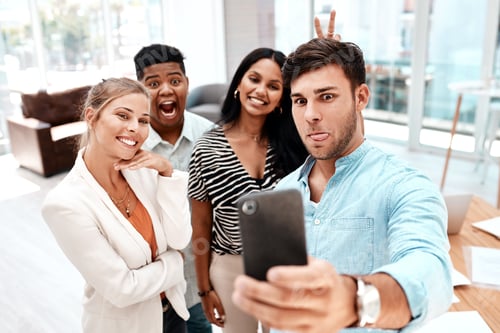 Preview: Cropped shot of a group of young business colleagues taking selfies in their office