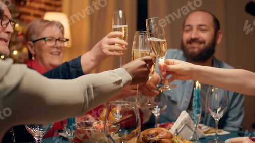 Preview: Festive family gathered at home to celebrate Christmas while toasting sparkling wine