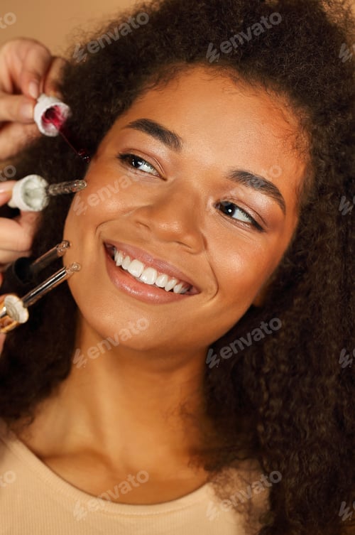 Preview: Young afro american lady posing with various pipettes of different essence serums near her face