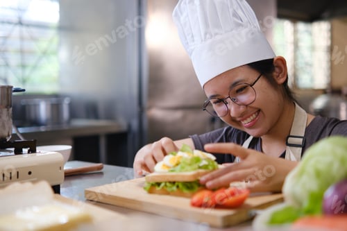Preview: Focused chef carefully a gourmet sandwich in a professional kitchen with fresh ingredients in view