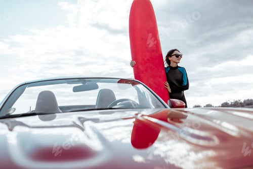 Preview: Young woman with surfboard on the rocky coast