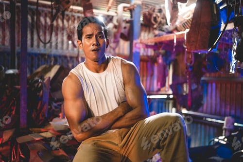 Preview: Young and handsome muscular and strop scrap material man in sleeveless shirt sitting on material