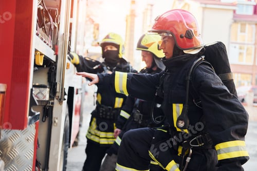 Preview: Group of firefighters in protective uniform that outdoors near truck