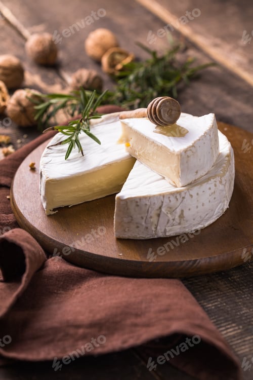 Preview: Organic farm camembert or brie cheese on a wooden board with rosemary and nuts, honey.