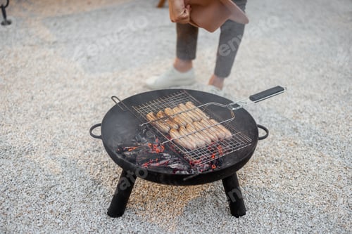 Preview: Man grilling sausages on a bbq bowl