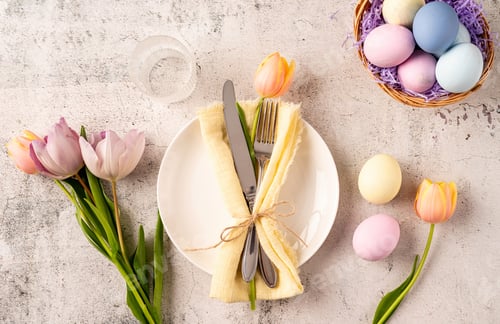 Preview: Table setting for Easter feast. Easter eggs, bunny, tulips and cutlery top view flat lay on concrete