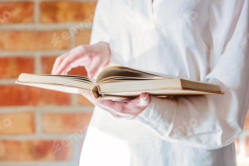 Preview: Woman in white shirt holding old book