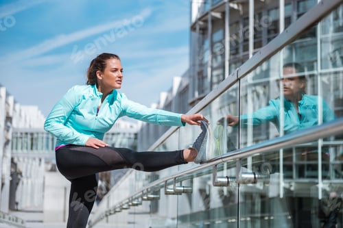 Preview: Young woman doing stretching exercise in the city