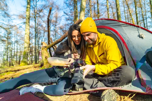 Preview: Smiling Couple Camping and Viewing Photos Together