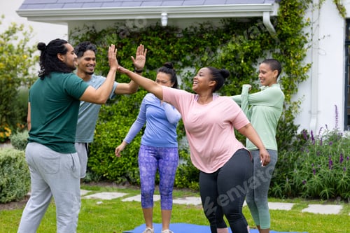 Preview: High-fiving outdoors, multiracial friends celebrating fitness and friendship together in park