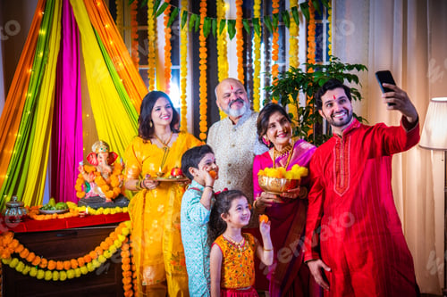 Preview: Indian Family Celebrating Ganesh Puja by Taking a Festive Selfie in Traditional Attire at Home