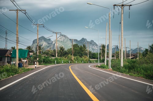 Preview: Asphalt road with mountain range and utility pole and lamppost in countryside at Sam Roi Yot