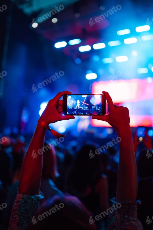 Preview: Hand with a phone records live music festival. People taking photographs with smart phone.