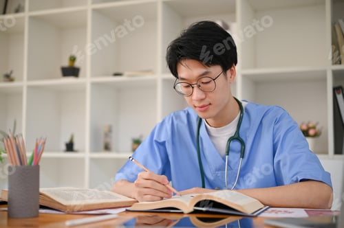 Preview: Smart Asian male medical student focuses on reading a book in the medical school library.