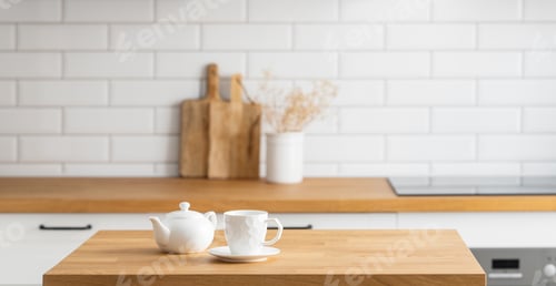 Preview: Wooden oak table with a cup of tea in front of the kitchen with a white brick background
